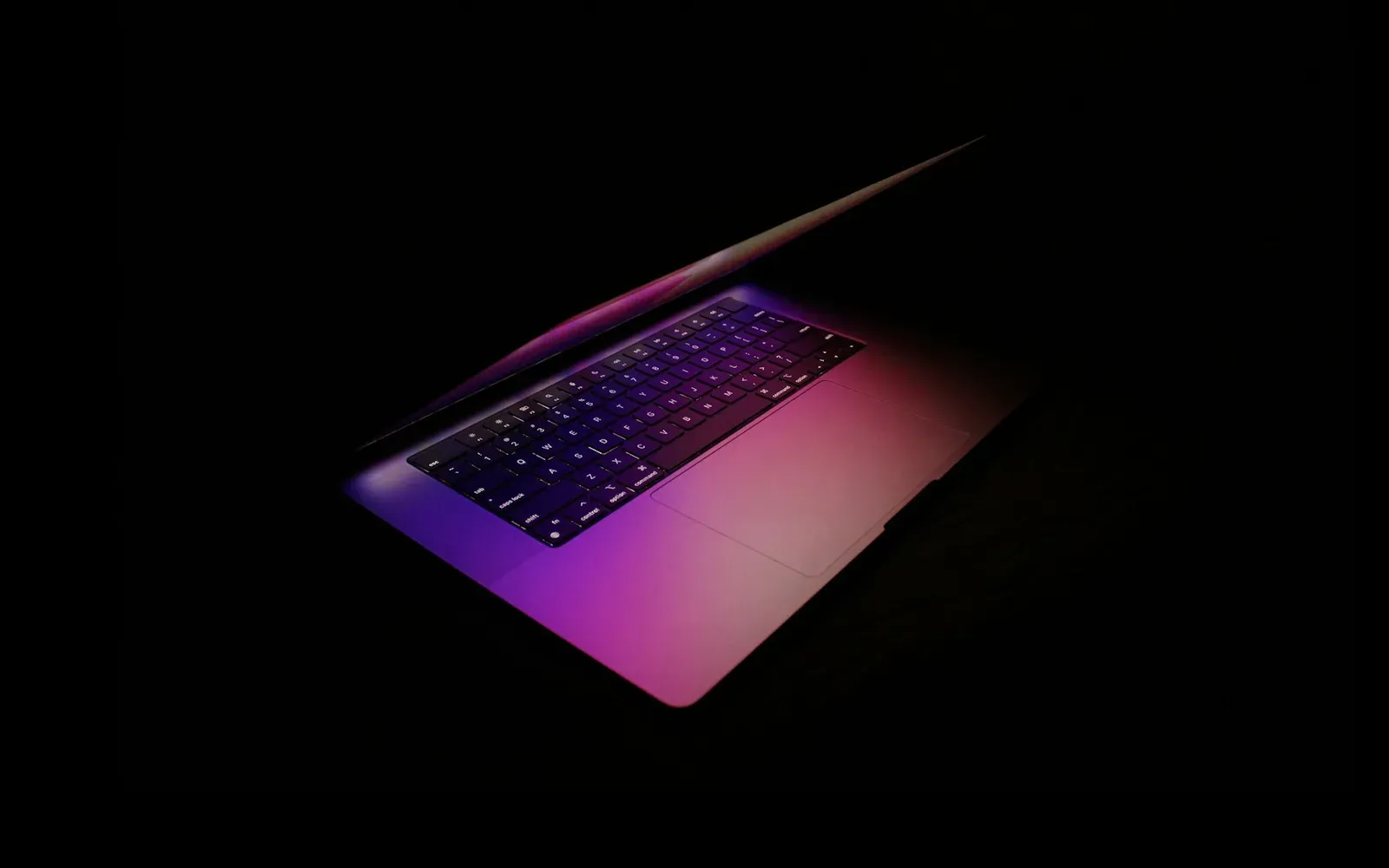 Aufgeklappter Laptop mit violett leuchtender Tastatur im Dunkeln – Domina finden