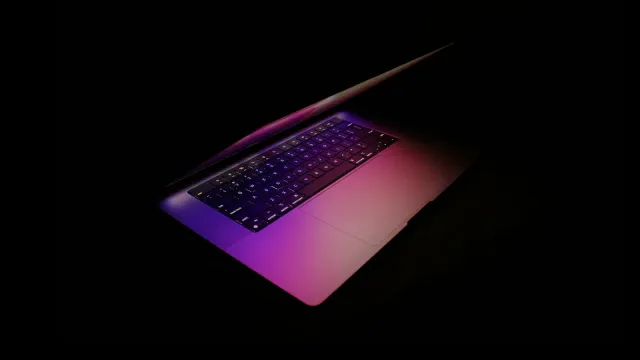 Aufgeklappter Laptop mit violett leuchtender Tastatur im Dunkeln – Domina finden