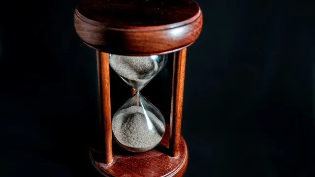 Sanduhr aus Holz und Glas vor schwarzem Hintergrund – Sinnbild für Warten und Verzögern bei Tease and Denial