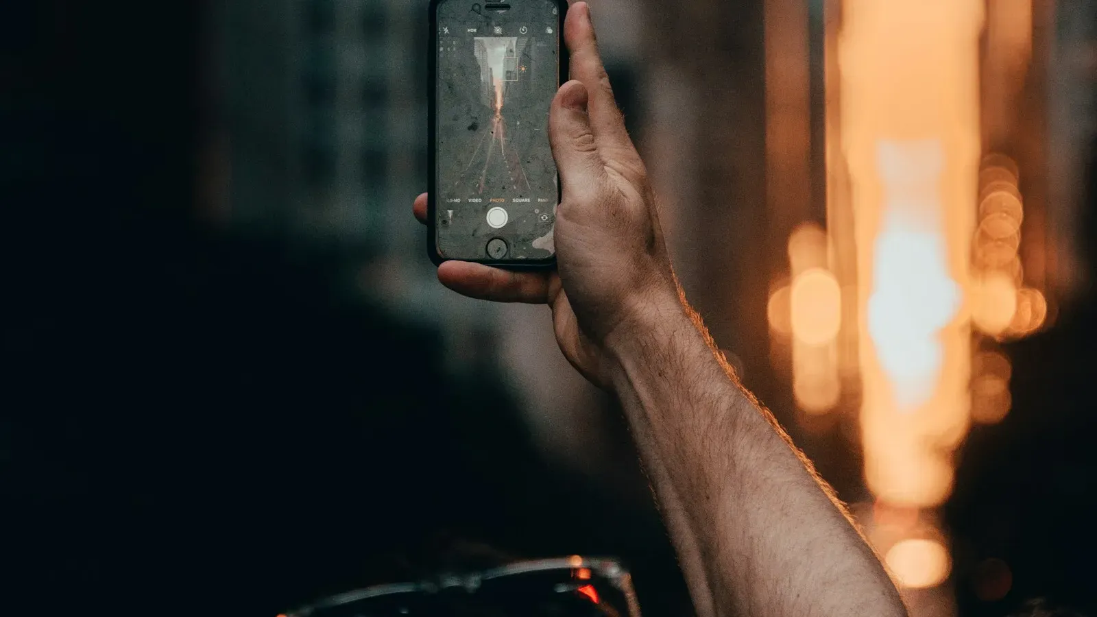 Hand hält ein leuchtendes Smartphone in der Nacht – Online-Erziehung im Chat