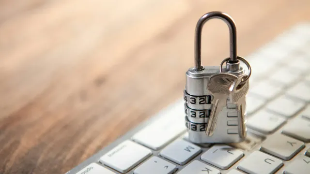 Kleines silbernes Vorhängeschloss mit zwei Schlüsseln auf einer Tastatur – Keuschheitsgürtel für Männer